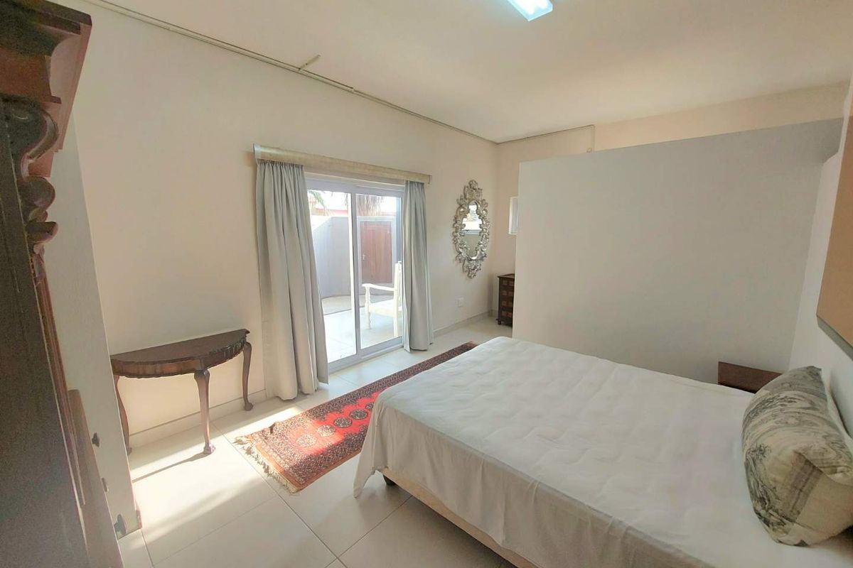 A bedroom featuring tiled flooring and a sliding glass door providing access to an outdoor area, with a partition wall creating a semi-private space.