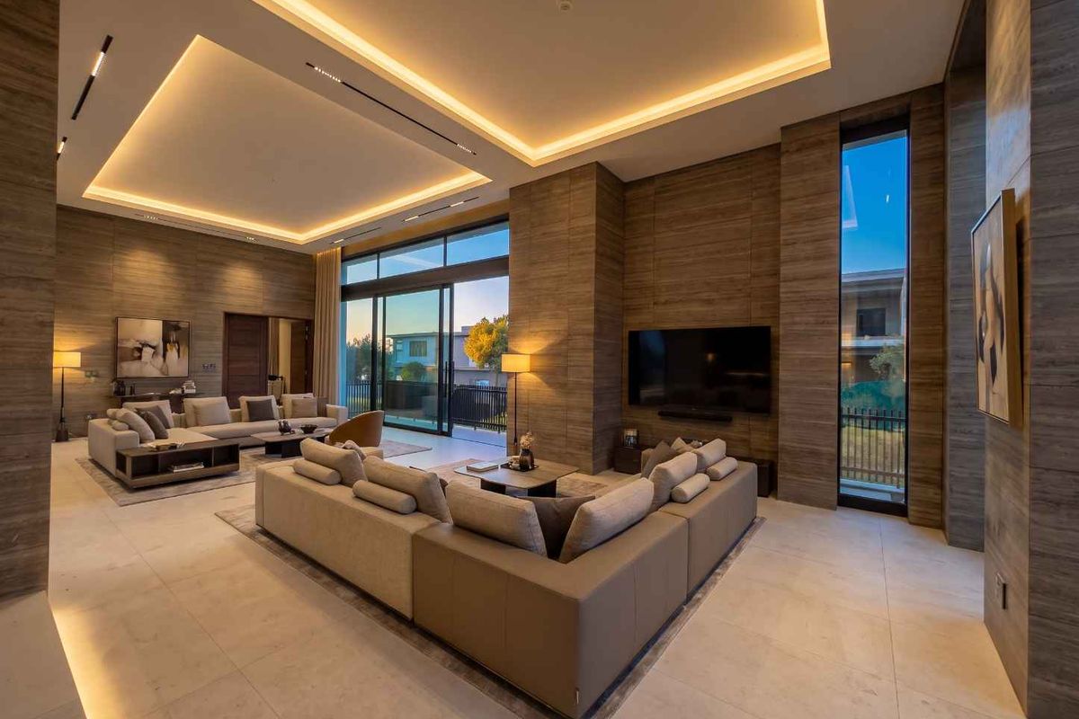 Spacious modern living room featuring high ceilings with recessed lighting, stone-clad feature walls, and large sliding glass doors opening to the exterior.