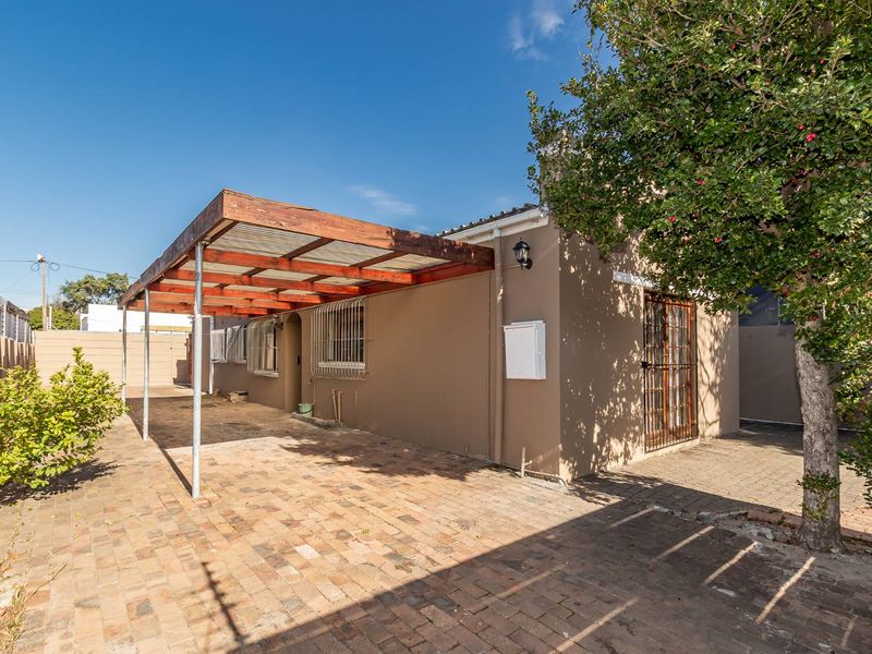 Rear exterior view featuring a brick-paved patio area with a timber pergola, security gates, and security bars on the windows.