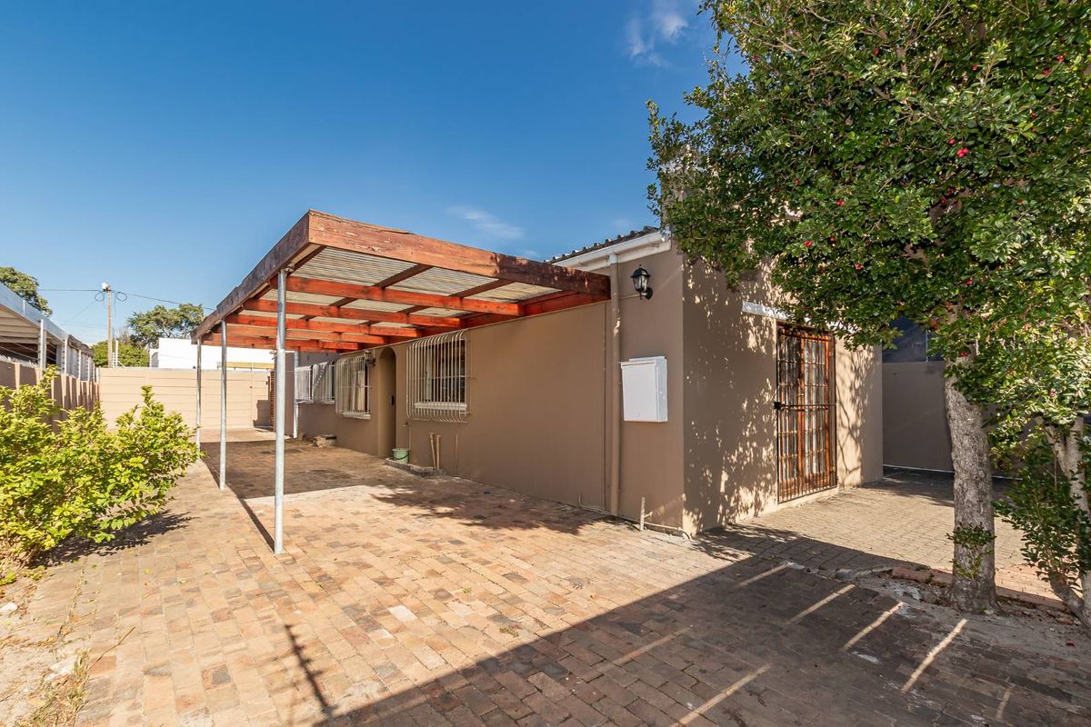 Rear exterior view featuring a brick-paved patio area with a timber pergola, security gates, and security bars on the windows.