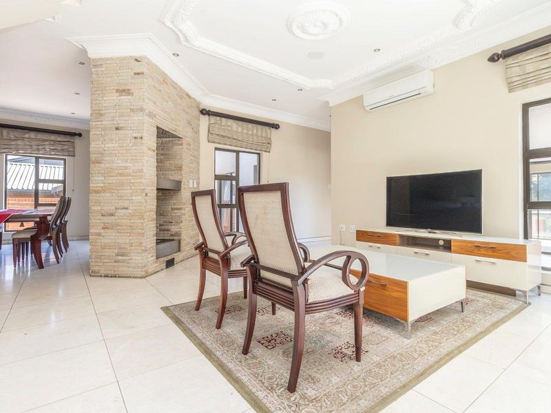 Spacious open-plan living area featuring a stone-clad fireplace, ornate ceiling detailing, tiled floors, and a split-system air conditioner.