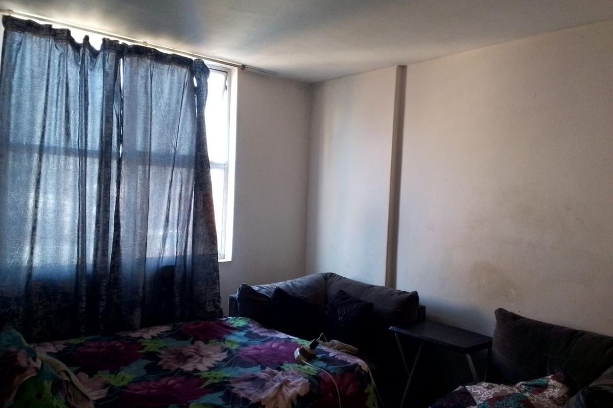 A bedroom featuring a large window with curtain rail, requiring cosmetic updates to the wall finishes to improve the overall aesthetic.