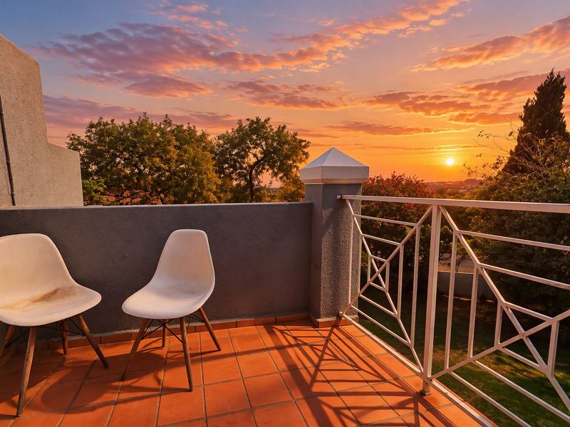 A private balcony featuring terracotta tiling and a metal balustrade, offering scenic sunset views over the surrounding garden and landscape.