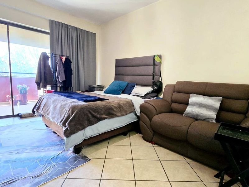 A bedroom featuring tiled flooring and a large sliding glass door providing access to an outdoor balcony area.