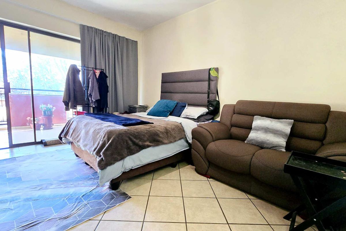 A bedroom featuring tiled flooring and a large sliding glass door providing access to an outdoor balcony area.