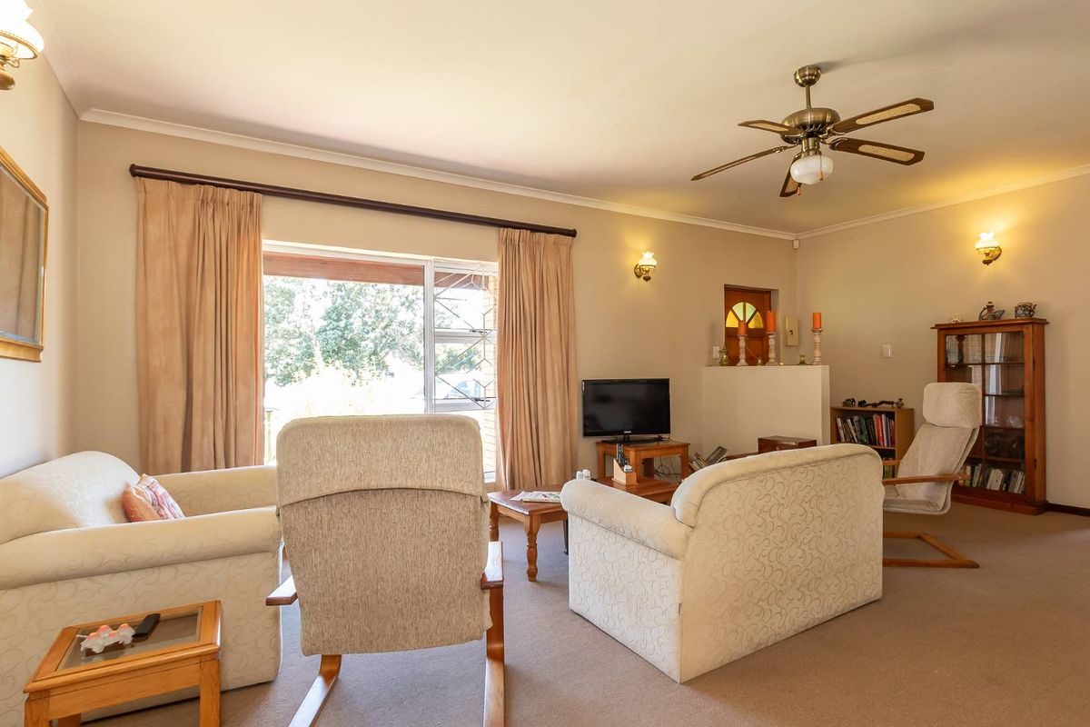 A comfortable living room featuring a ceiling fan, wall-mounted lighting, and large sliding glass doors that provide access to the outdoor area.