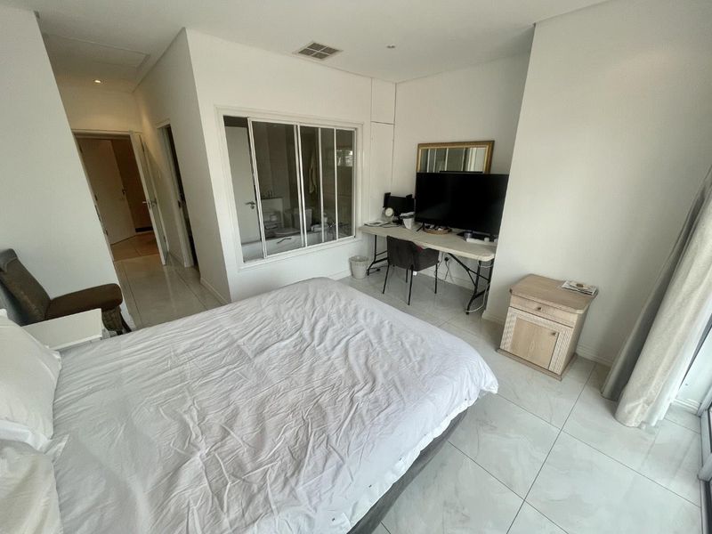 A bedroom featuring tiled flooring, recessed lighting, and a unique glass partition wall looking into the bathroom area.