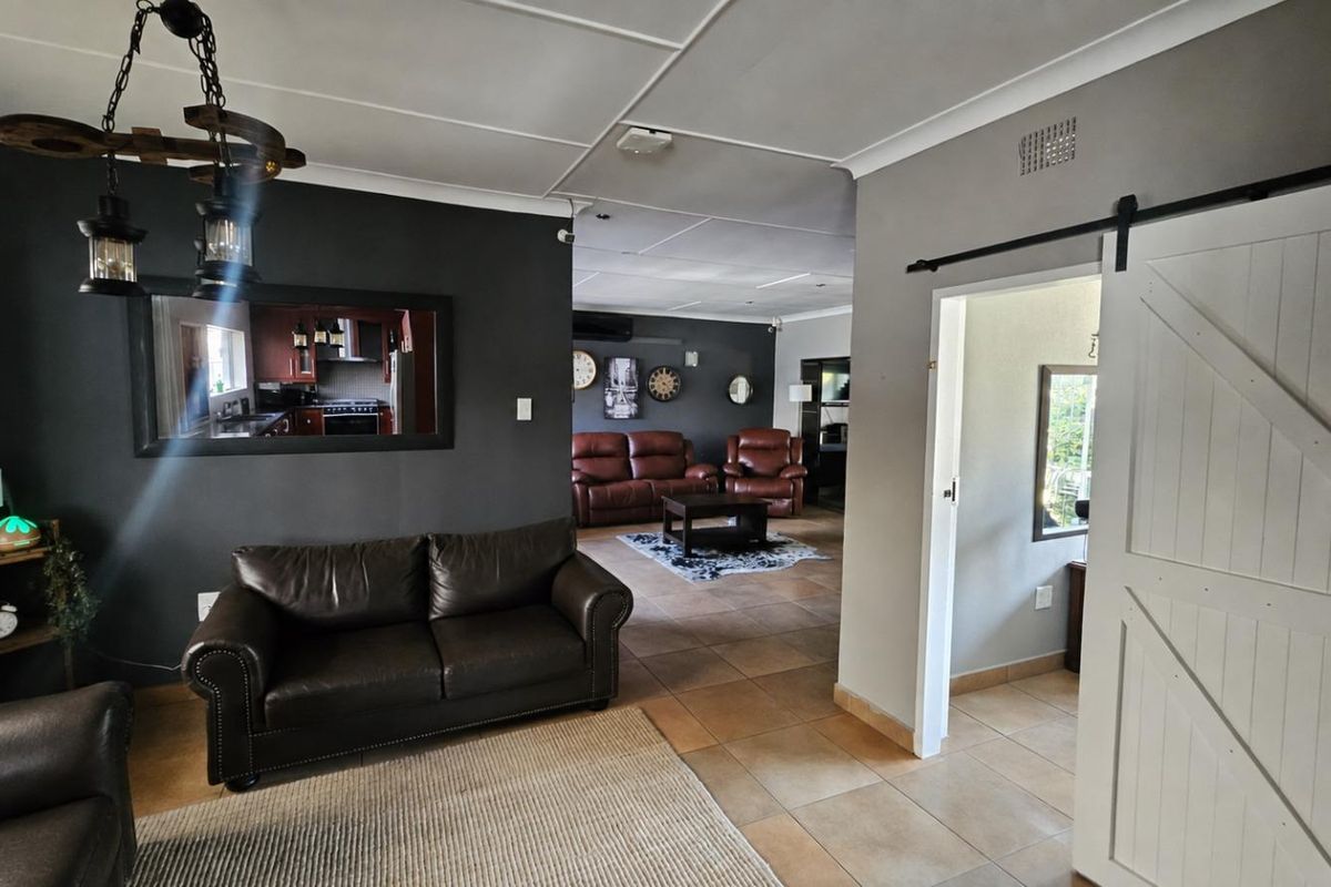 Spacious living area featuring tiled flooring, a sliding barn door, and neutral wall tones, providing a comfortable and functional layout.