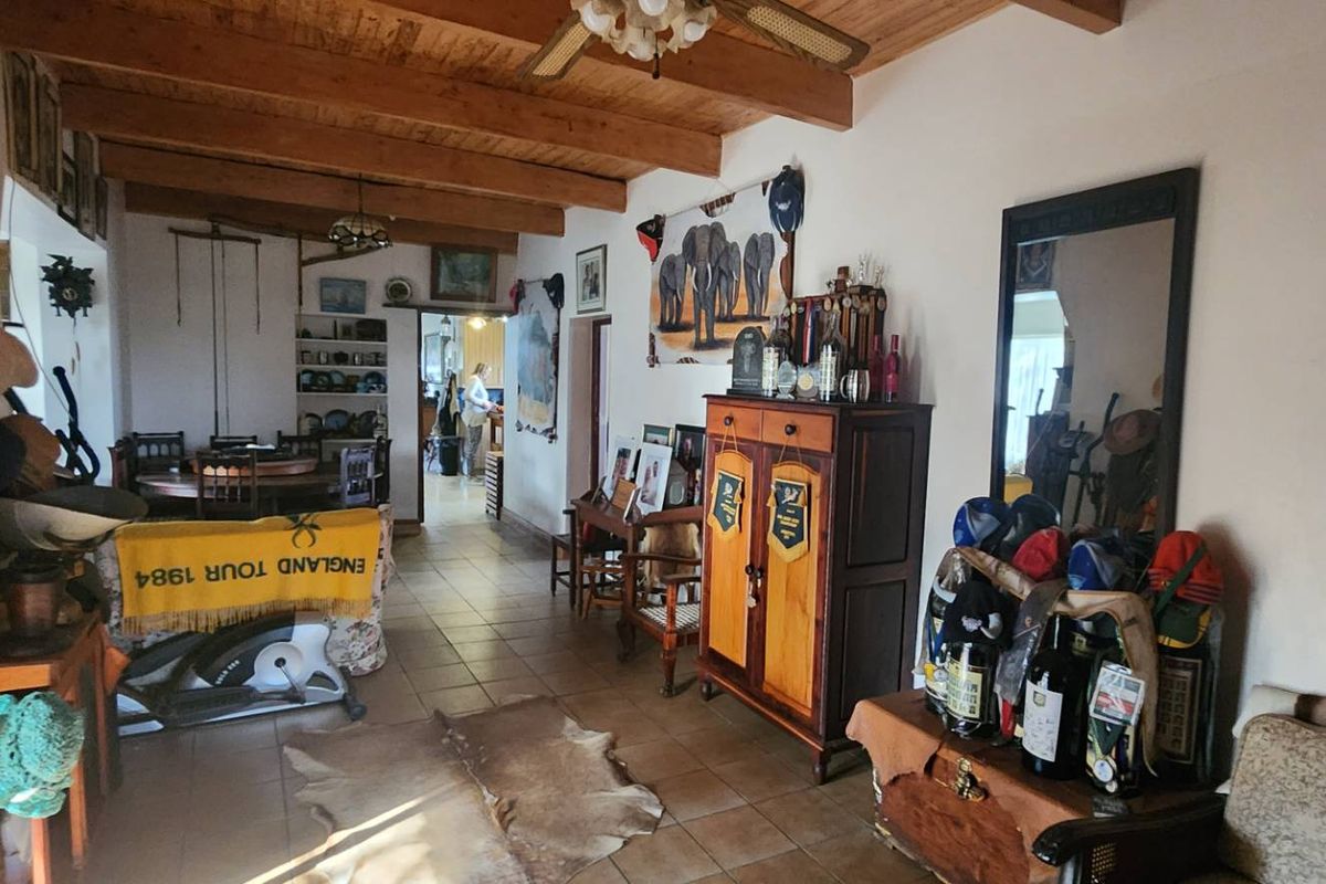 Spacious living area featuring rustic exposed timber ceiling beams, tiled flooring, and a ceiling fan, offering a warm and traditional farm-style atmosphere.