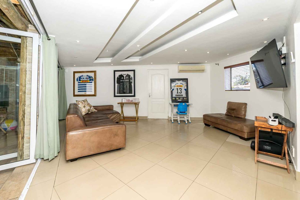 Spacious living room featuring tiled flooring, recessed ceiling lighting, and a wall-mounted air conditioning unit, with direct access to an outdoor patio area.