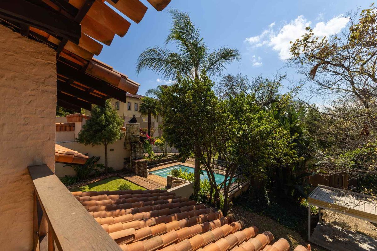 Elevated view of a rear garden featuring a swimming pool, brick chimney, and traditional terracotta roof tiles.
