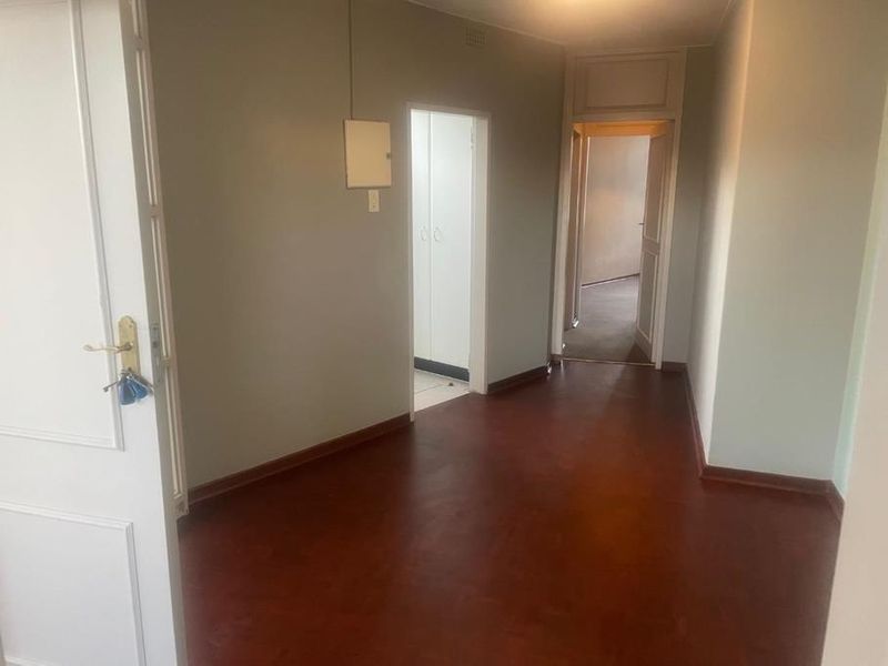 A vacant hallway featuring timber flooring and access to multiple rooms, providing a neutral foundation for interior design.