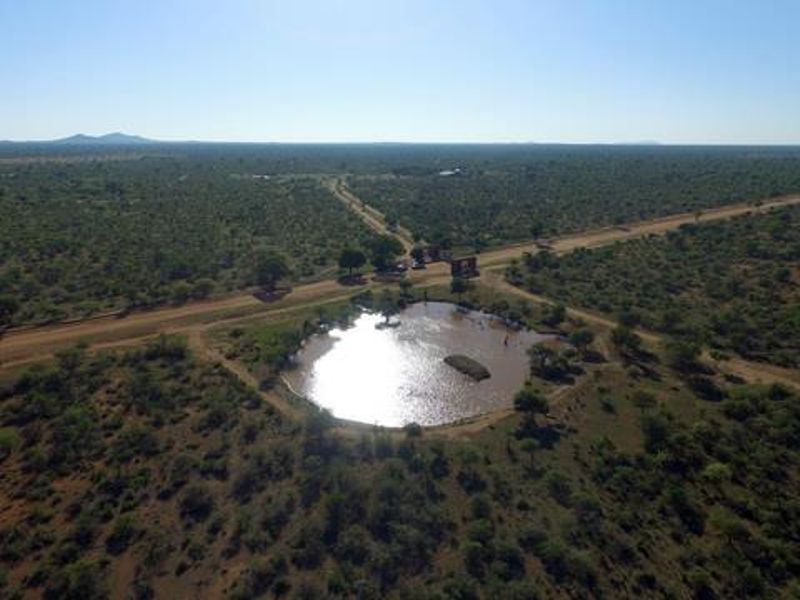 An aerial view of the farm property showcasing the expansive landscape, a natural water dam, and the access road.