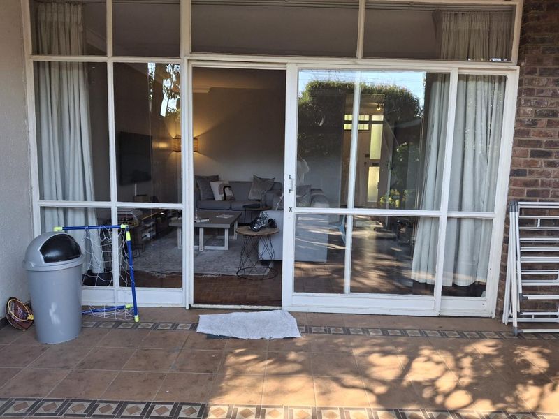 A covered patio area featuring tiled flooring and large sliding glass doors providing access to the interior living space.