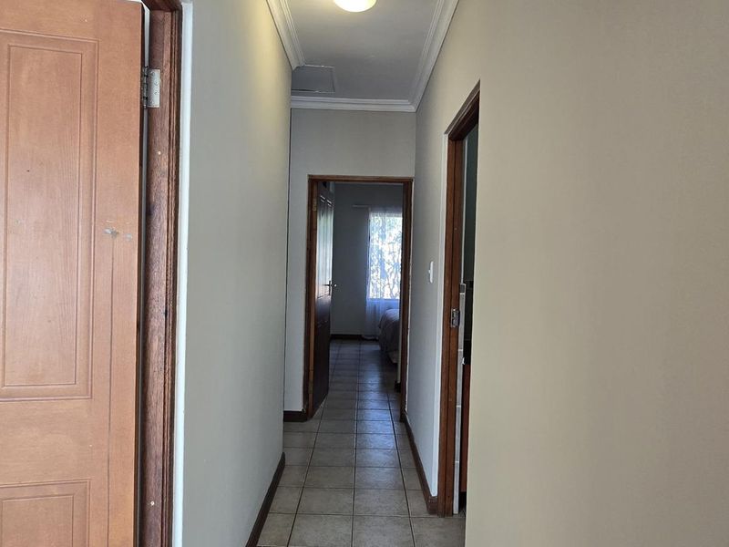 A functional hallway featuring tiled flooring and timber door frames, providing access to multiple rooms within the townhouse.