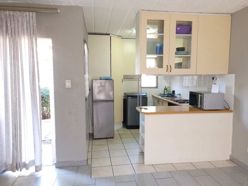 A functional kitchen featuring built-in cabinetry, a breakfast counter, tiled flooring, and a tiled backsplash, offering a practical layout for daily use.