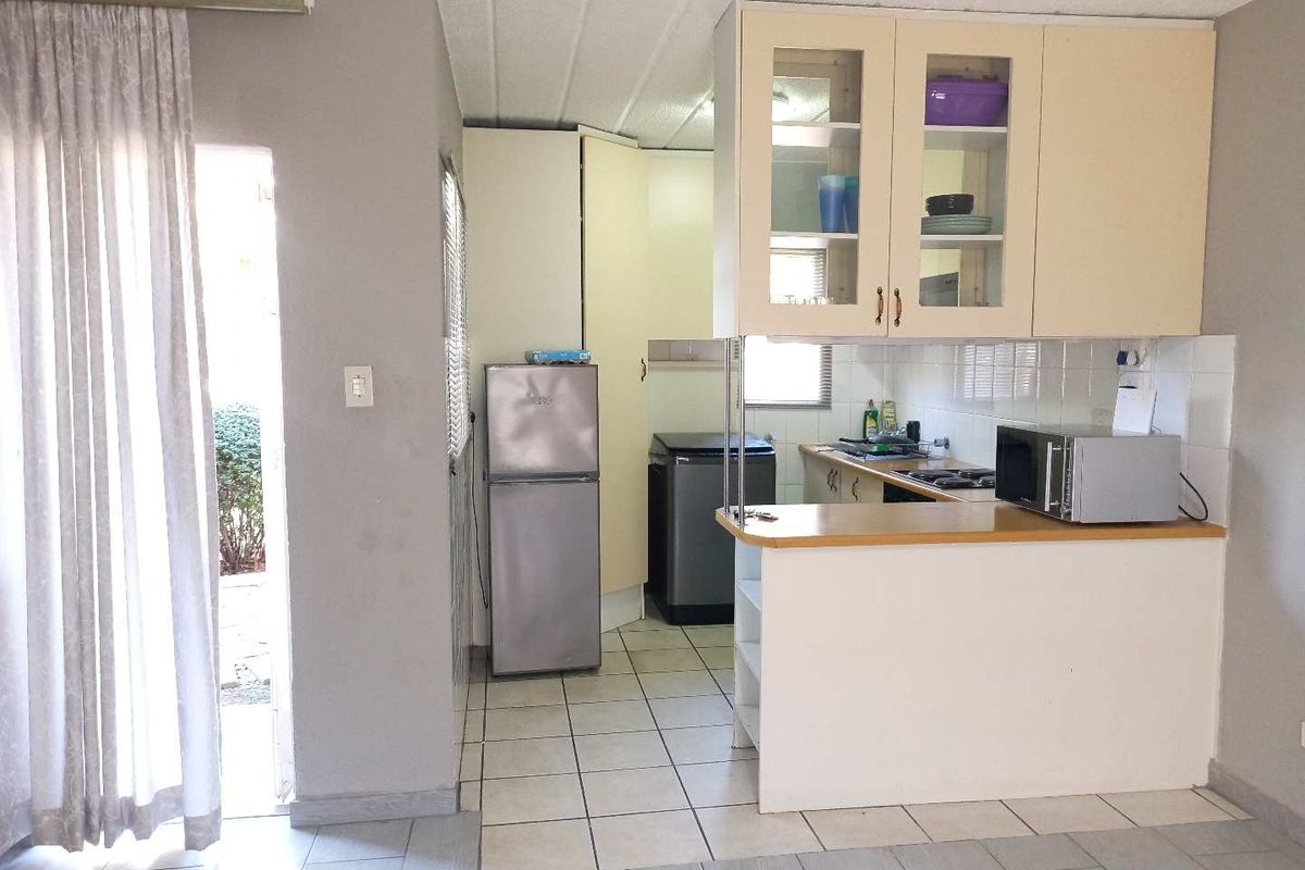A functional kitchen featuring built-in cabinetry, a breakfast counter, tiled flooring, and a tiled backsplash, offering a practical layout for daily use.