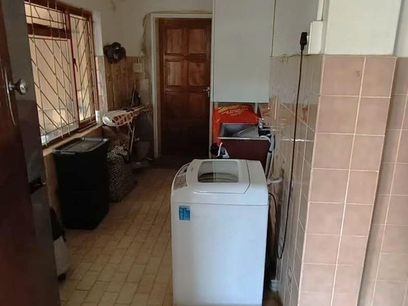 A functional laundry area featuring tiled walls, built-in sink, and direct access to the exterior, providing a practical space for household utility tasks.