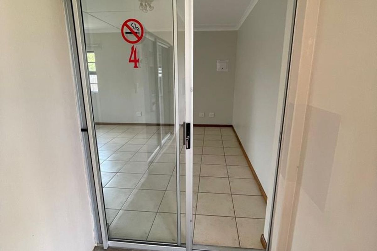 An interior view of an empty room featuring tiled flooring and a sliding glass door entrance.