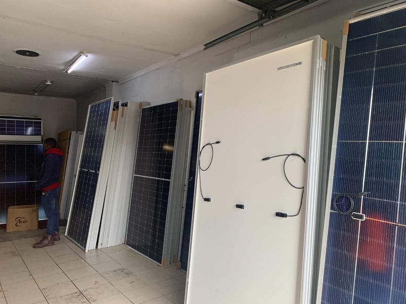 A utility space currently used for the storage of solar panels, featuring tiled flooring and overhead fluorescent lighting.