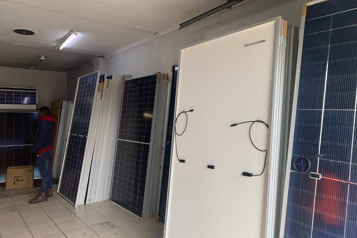 A utility space currently used for the storage of solar panels, featuring tiled flooring and overhead fluorescent lighting.