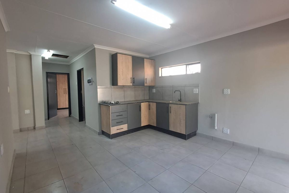 A clean, modern kitchen featuring two-tone cabinetry, tiled flooring, and essential built-in fixtures, offering a functional and neutral space ready for personalization.