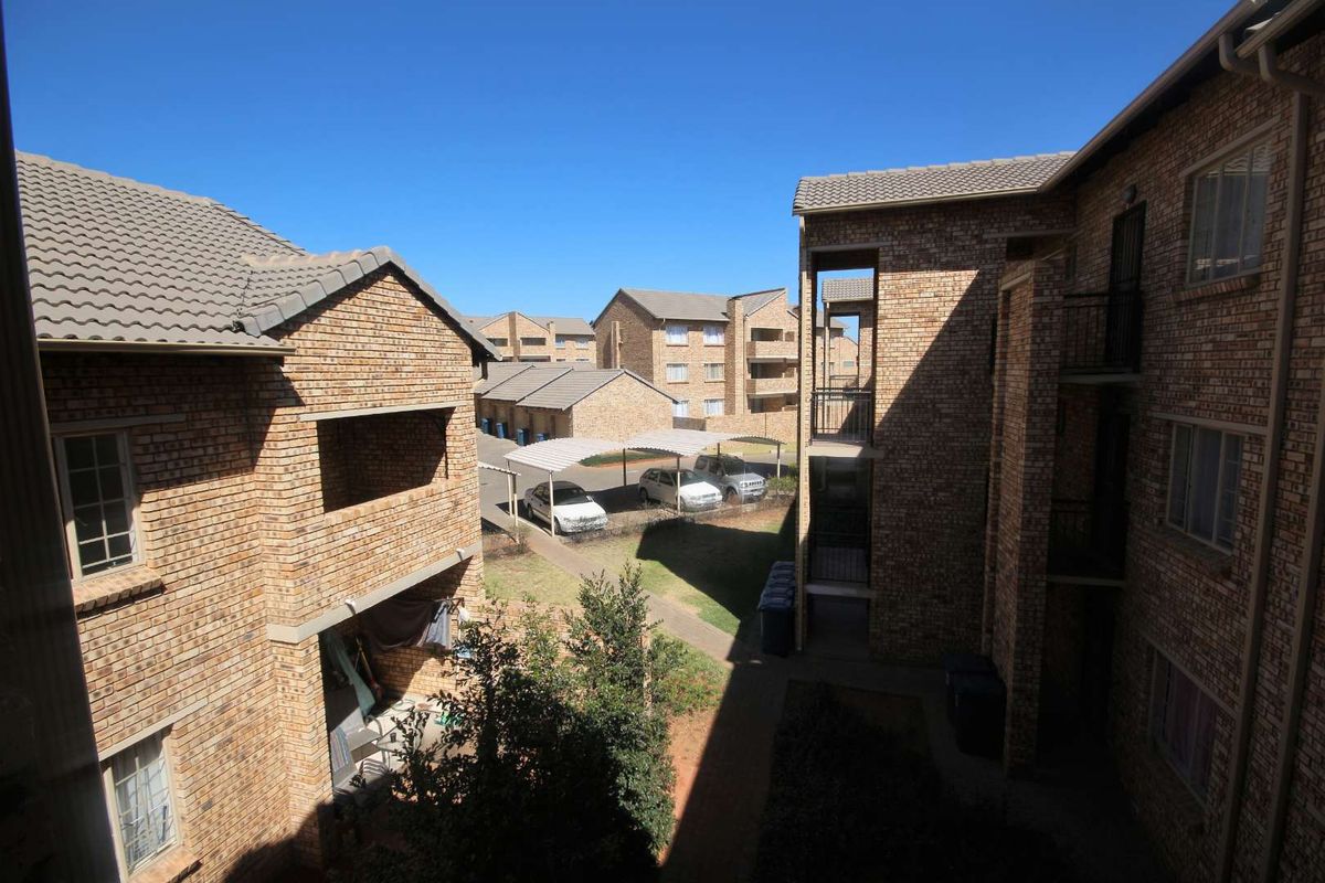 An elevated view of the apartment complex courtyard featuring face brick buildings, tiled roofs, and covered parking areas.