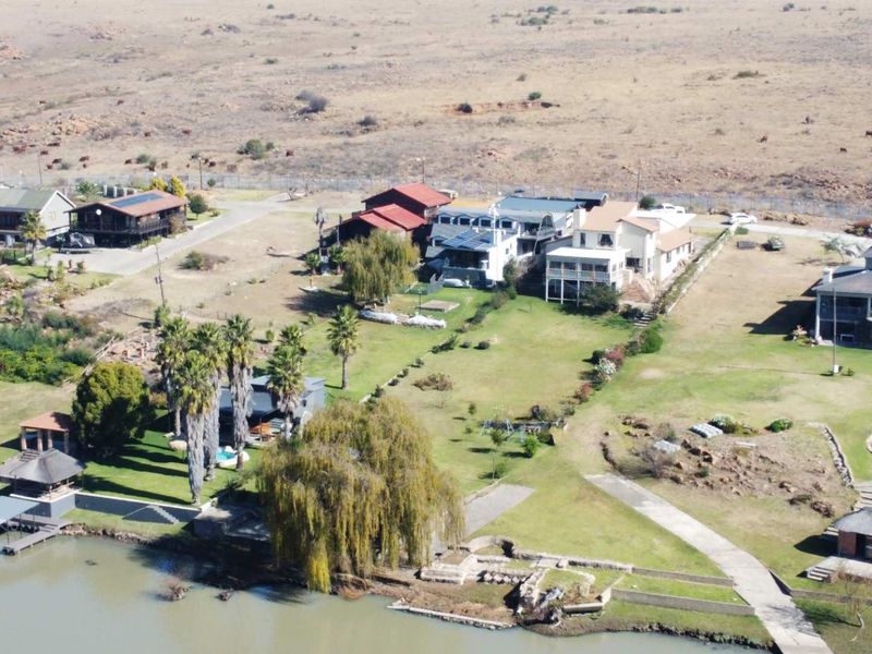 Aerial view of a waterfront property featuring expansive garden grounds, paved access, and direct river frontage in a rural estate setting.