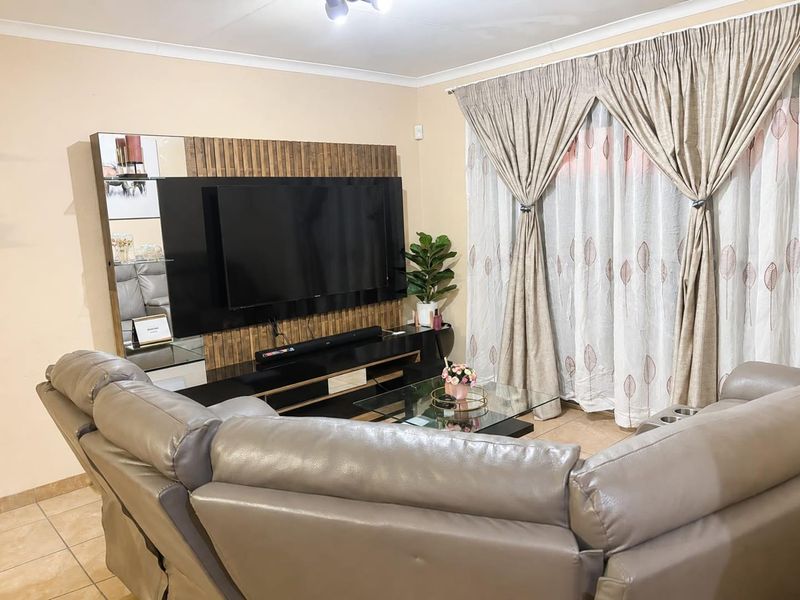 A comfortable living room featuring tiled flooring, cove cornicing, and a modern built-in media wall unit with integrated shelving.