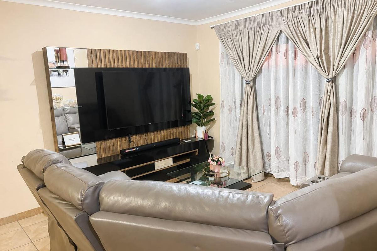 A comfortable living room featuring tiled flooring, cove cornicing, and a modern built-in media wall unit with integrated shelving.