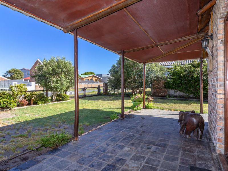 A covered outdoor patio area featuring tiled flooring and direct access to the rear garden through timber-framed glass doors.
