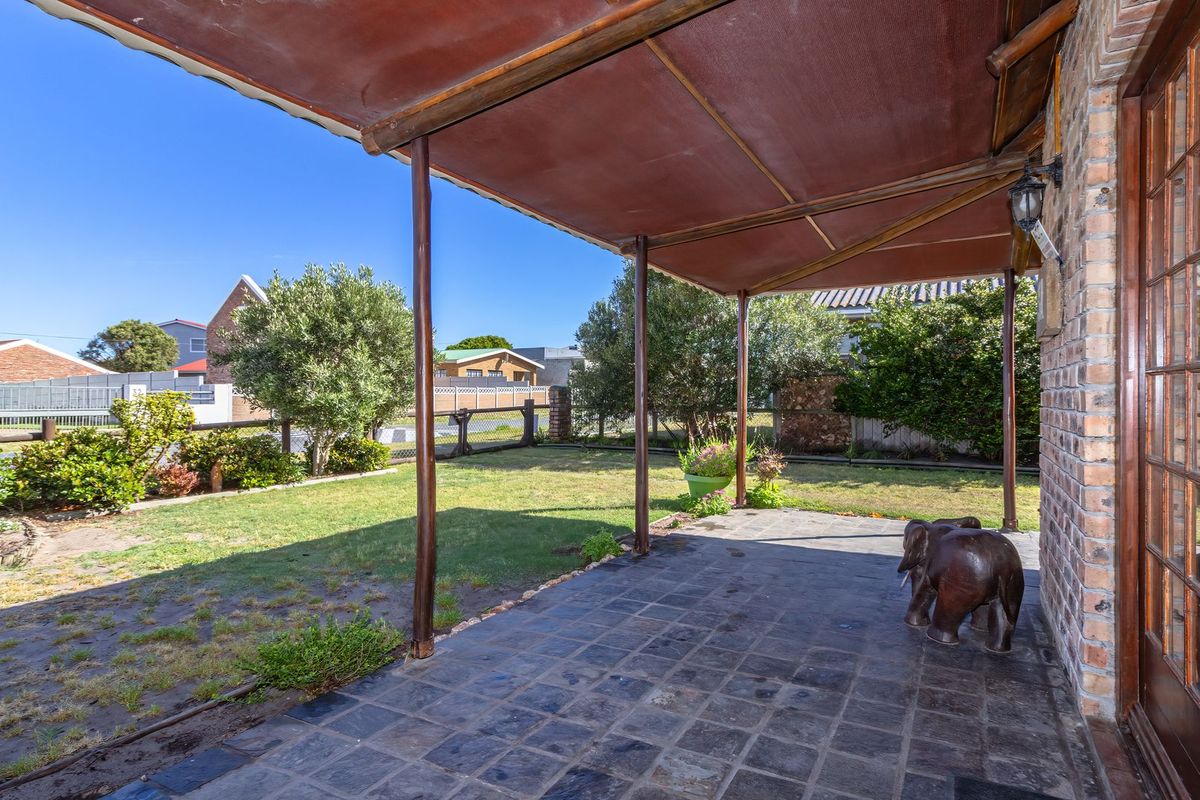 A covered outdoor patio area featuring tiled flooring and direct access to the rear garden through timber-framed glass doors.