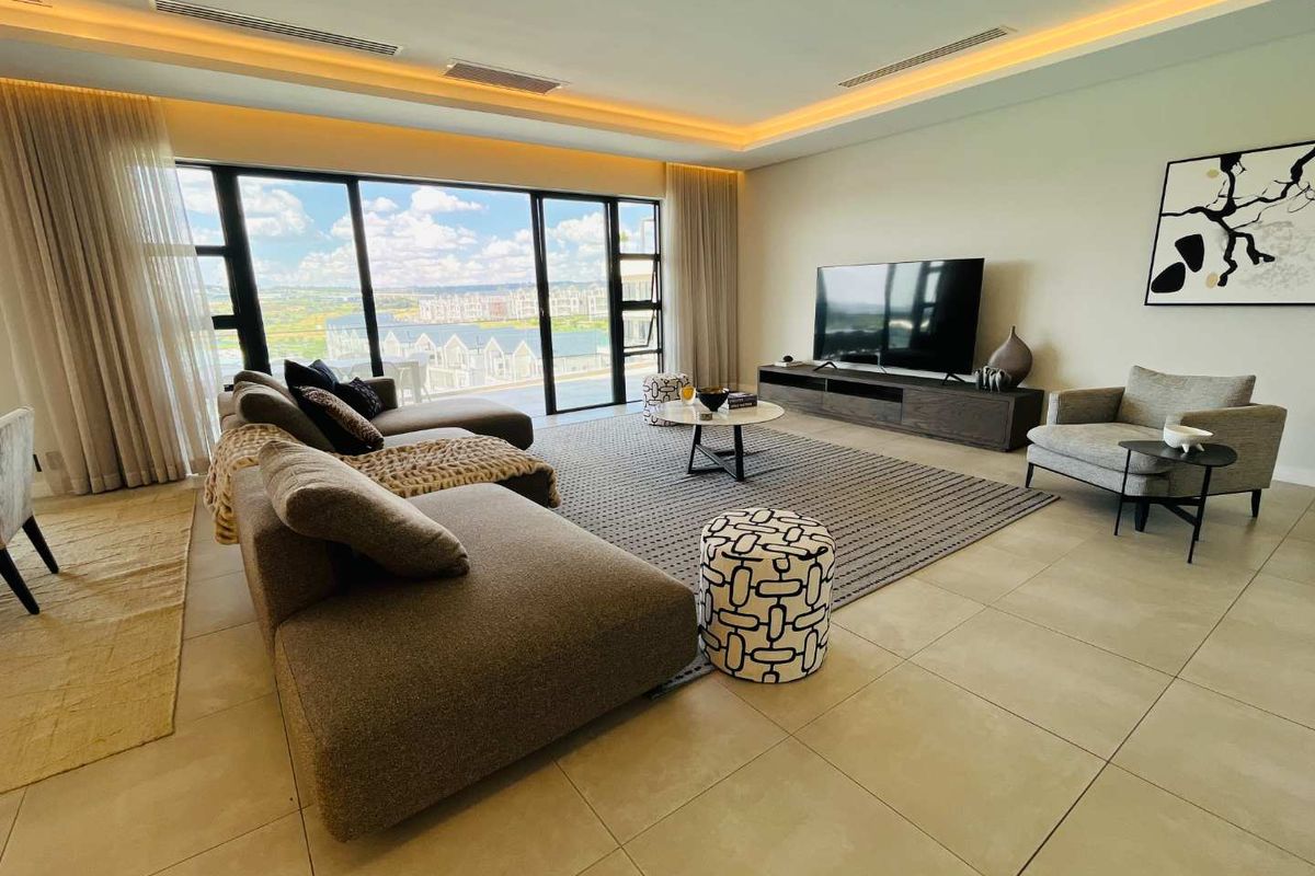 Spacious modern living room featuring large sliding glass doors with scenic views, recessed ceiling lighting, and neutral tiled flooring.