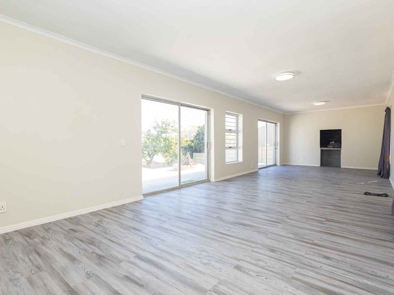 Spacious, light-filled living area featuring modern laminate flooring, built-in fireplace, and large sliding glass doors providing access to the outdoor space.