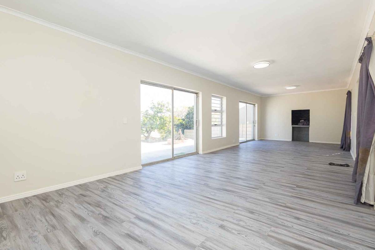 Spacious, light-filled living area featuring modern laminate flooring, built-in fireplace, and large sliding glass doors providing access to the outdoor space.