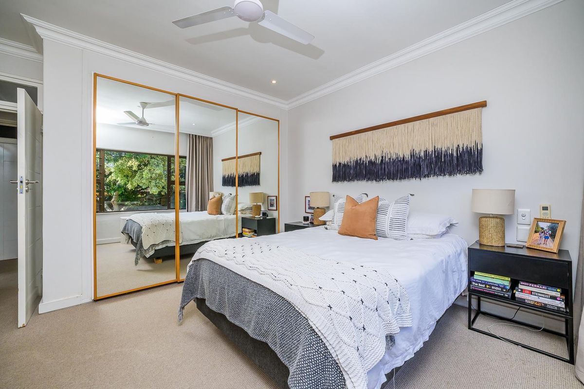 A well-maintained bedroom featuring built-in mirrored wardrobes, crown molding, and a ceiling fan, offering a bright and comfortable living space.