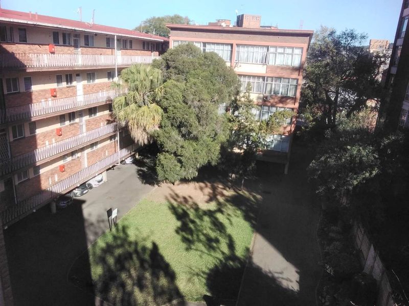 An elevated view of the apartment complex rear courtyard featuring brick facades, communal garden space, and balcony access.