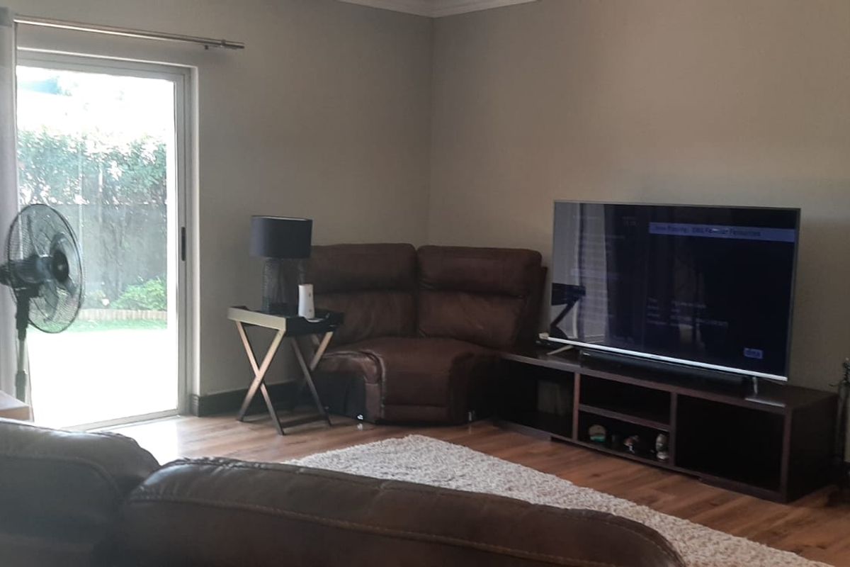 A comfortable living room featuring laminate flooring and a sliding glass door providing direct access to the outdoor area.