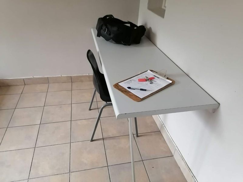 A small office space featuring a wall-mounted desk and ceramic tiled flooring.