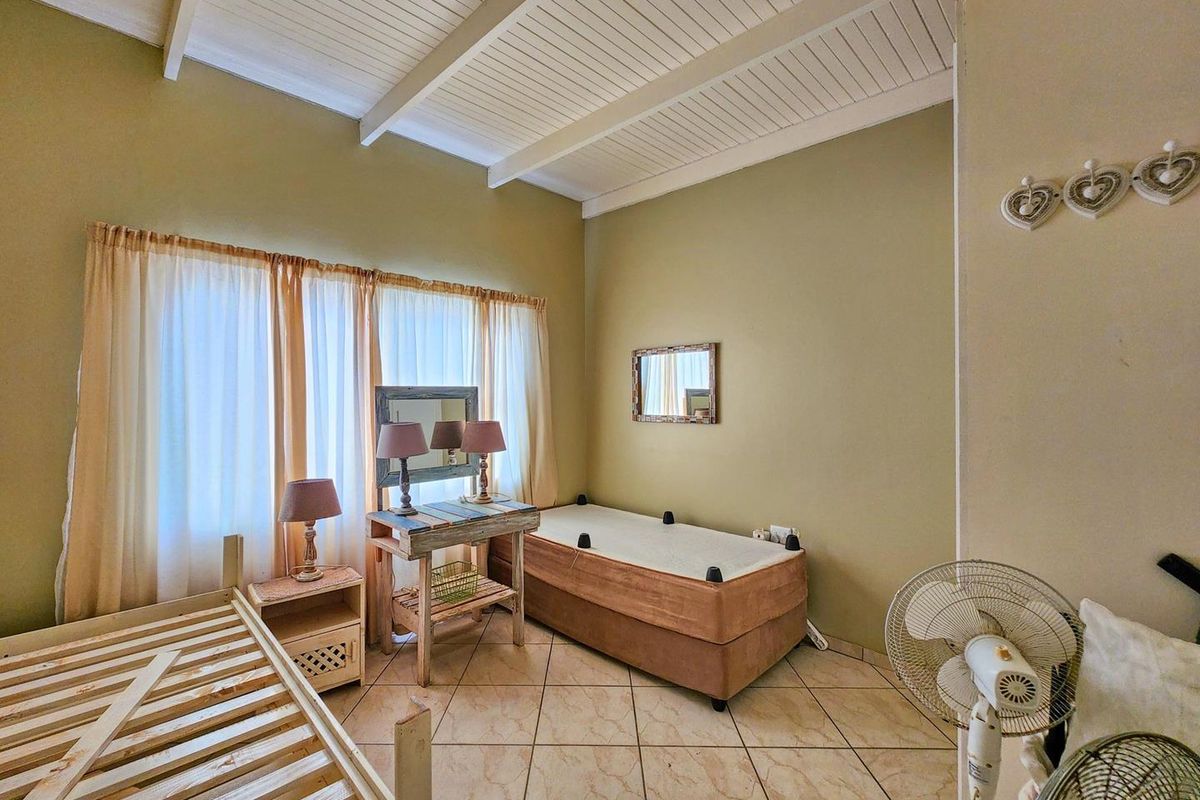 A bedroom featuring high vaulted ceilings with exposed beams, tiled flooring, and large windows allowing for natural light.