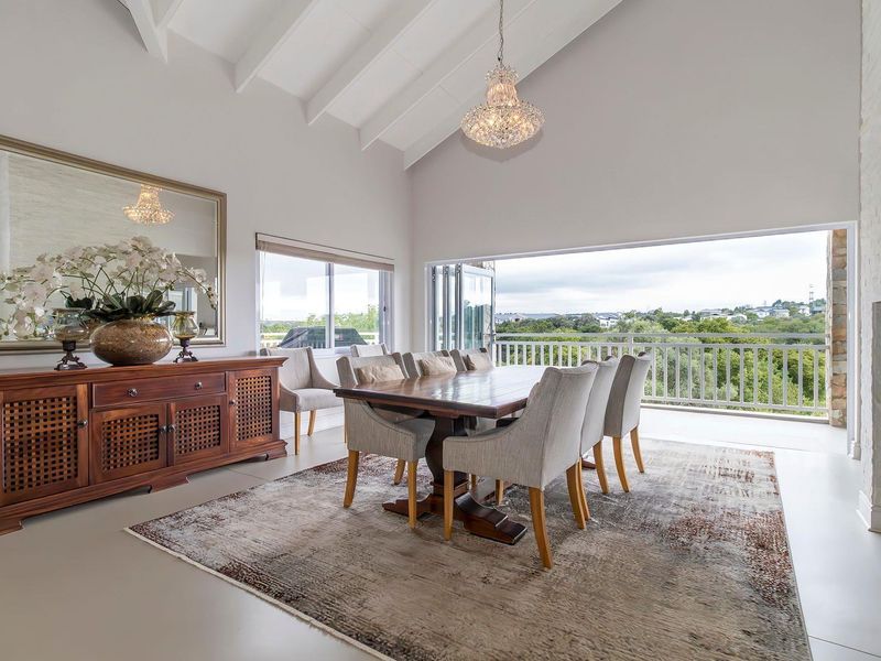 Spacious dining area featuring vaulted ceilings, a built-in fireplace, and large folding doors opening onto a balcony with scenic views.