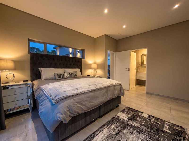 A well-maintained bedroom featuring tiled flooring, recessed downlighting, a modern clerestory window, and direct access to an en-suite bathroom.