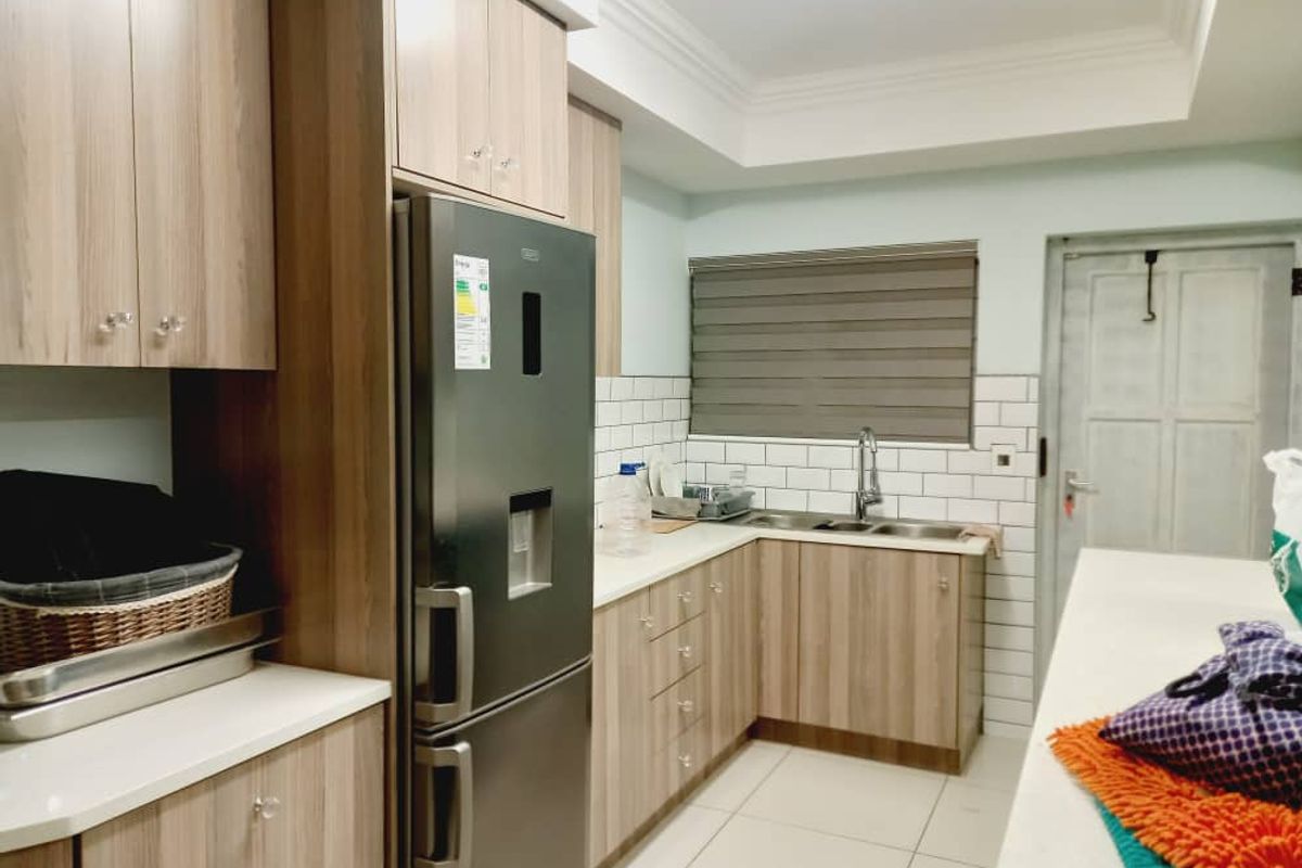 Modern kitchen featuring wood-grain cabinetry, white subway tile backsplash, stone countertops, and a double-basin sink with a contemporary faucet.