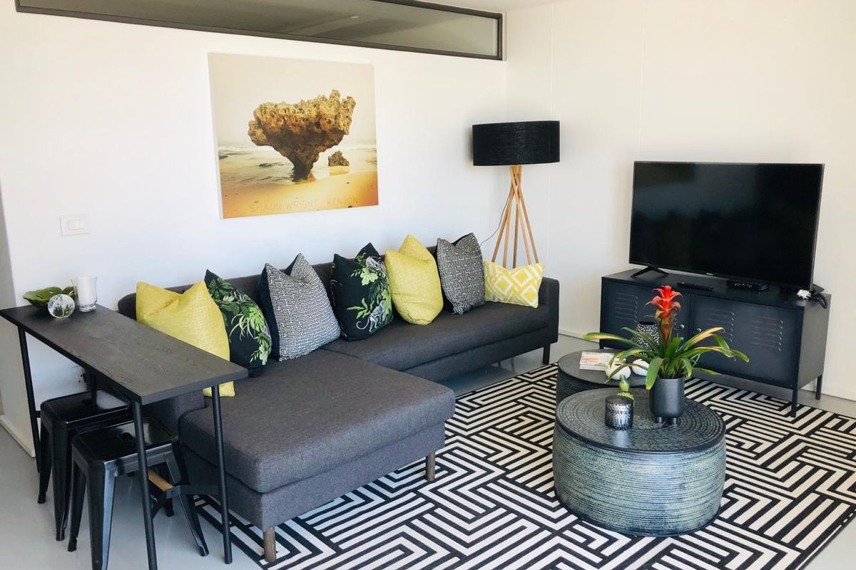 A modern living room featuring clean white walls, recessed ceiling detailing, and a high-level clerestory window providing natural light.