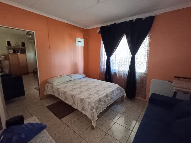 A bedroom featuring tiled flooring and an exposed electrical distribution board, requiring cosmetic updates to improve the overall aesthetic and condition.