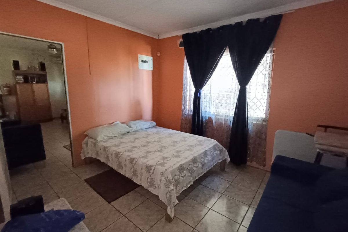 A bedroom featuring tiled flooring and an exposed electrical distribution board, requiring cosmetic updates to improve the overall aesthetic and condition.