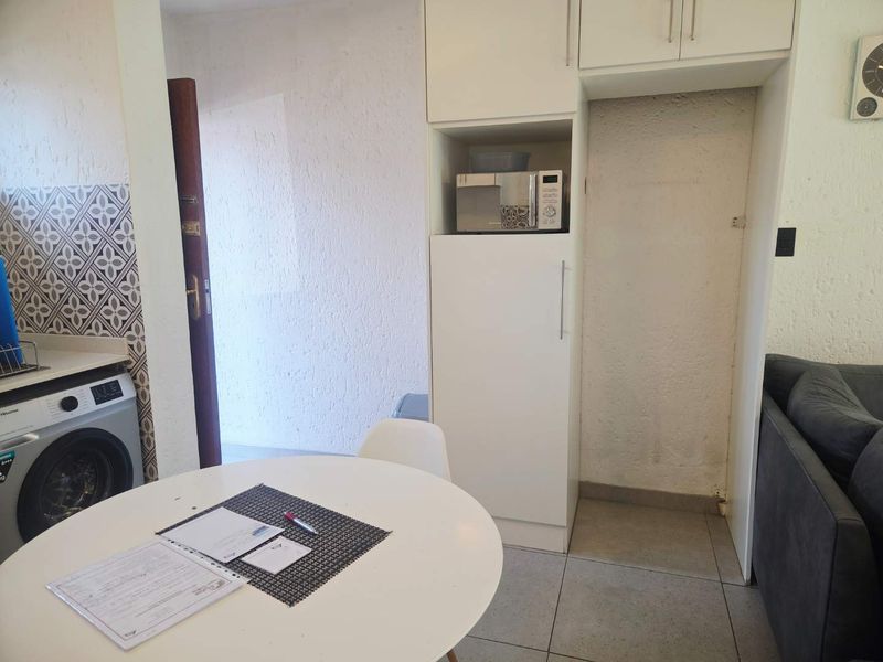 A functional kitchen area featuring built-in cabinetry, a tiled backsplash, and dedicated space for appliances, with tiled flooring throughout.