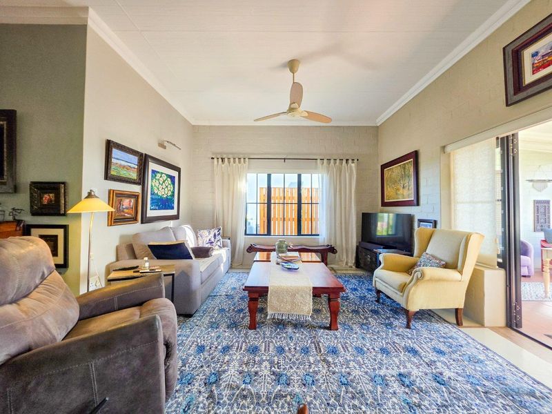 A comfortable living room featuring painted brick walls, a ceiling fan, and large sliding glass doors that provide access to the outdoor area.