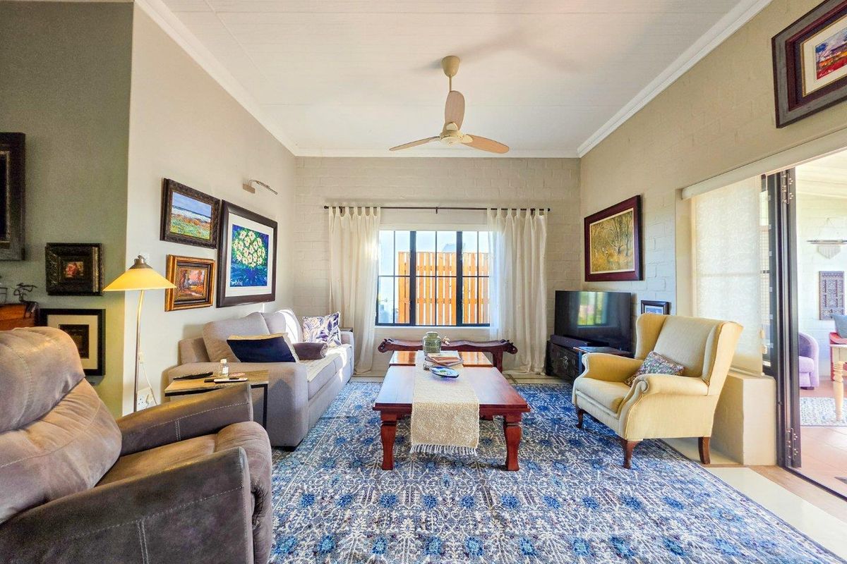 A comfortable living room featuring painted brick walls, a ceiling fan, and large sliding glass doors that provide access to the outdoor area.