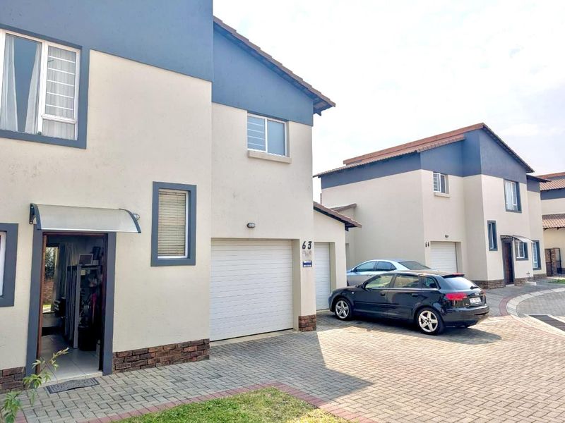 Front elevation of a modern double-story townhouse featuring a double garage, paved driveway, and neutral exterior paint finish.